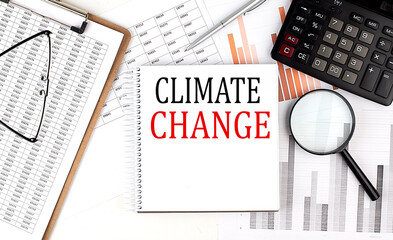 CLIMATE CHANGE text on notebook with clipboard and calculator on a chart background