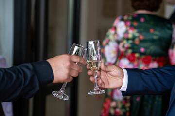 Closeup of male hands holding champagne glasses and cheering