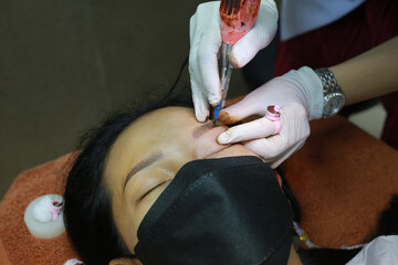 Close-up Asian woman with tattoo eyebrows. Permanent makeup by professional cosmetologist.
