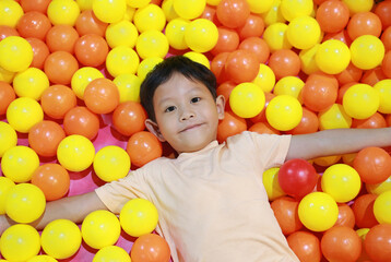 Asian little boy playing at colorful plastic balls playground.