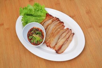 Grilled pork, Roasted pork neck with spicy sour dipping sauce in white plate on wood background.