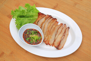 Grilled pork, Roasted pork neck with spicy sour dipping sauce in white plate on wood table. Thai food.