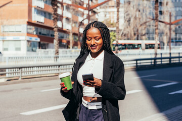 Cheerful black woman with smartphone on street