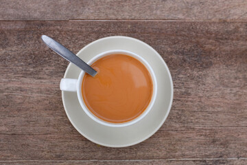 Tea with milk in porcelain cup on wood table background. Top view.