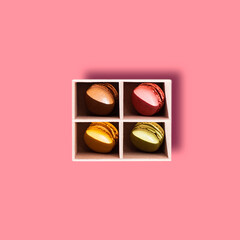 Colourful French macaroon, a sweet meringue-based confection, placed in a box on a colourful background.