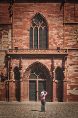Vertical shot of a tourist making a photo in front of the Basel Minster in Basel, Switzerland