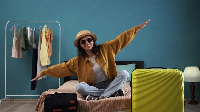 Ready for adventure. Happy woman preparing for the journey packing suitcase for the trip, looking like plane imagines herself flying, playing airplane, imagining travelling or having fun