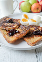 French toast with blueberry jam and boiled eggs on a plate for breakfast