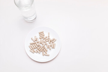 Top View Handful Of Pills, Capsules OF Slippery Elm And Glass Of Water. Dietary Nutritional Supplement, Medication. Ulmus Fulva, Herbal Remedy Concept. Horizontal Plane, Copy space For Text