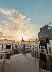 Fototapeta premium Vertical back view of a young male overlooking a beautiful sunset in an old city