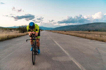  Triathlete riding his bicycle during sunset, preparing for a marathon. The warm colors of the sky...
