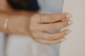 Vertical shot of a woman showing her jewelry against a blurred beige background