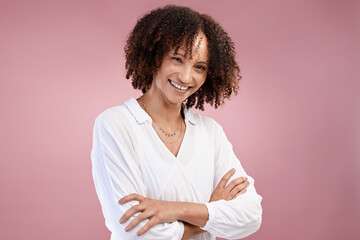 Full of confidence. Cropped portrait of an attractive young woman standing with her arms folded in studio against a pink background.