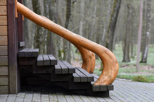 Bent wooden log used as creative rustic railing to staircase to the cottage house. Selective focus.