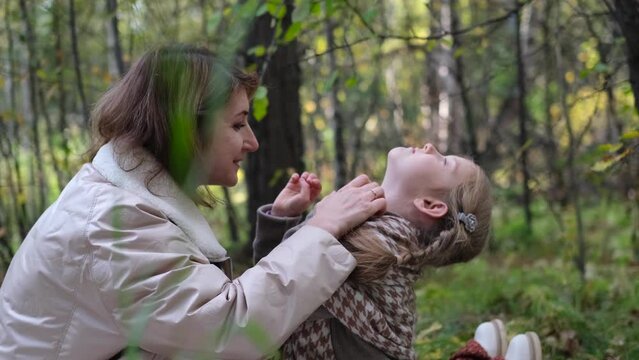 Hello September. A young mother and little daughter walk in the city park in autumn.