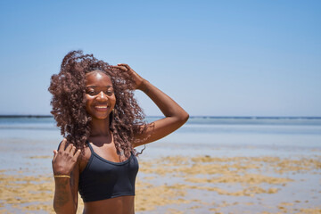 oung smiling brazilian woman on summer vacation standing at beach and enjoying sea breeze.Sexy bikini body woman feeling free on holidays.                          