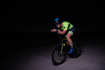 A triathlete rides his bike in the darkness of night, pushing himself to prepare for a marathon....