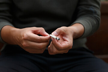 Man holding broken cigarette in hands. Stop smoking cigarettes concept. No smoking campaign concept.