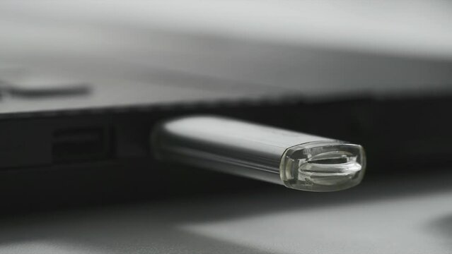 technology, woman hand includes a flash drive for data transfer in a laptop, red light flashes on a flash drive, close-up