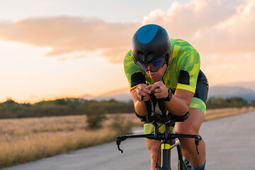  Triathlete riding his bicycle during sunset, preparing for a marathon. The warm colors of the sky...