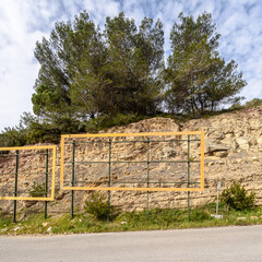 Empty orange billboards against a rock face with a cloudy blue sky above them