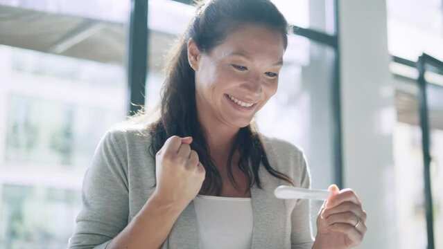 Video of happy woman celebrating while looking at predictor finding out she is pregnant at home