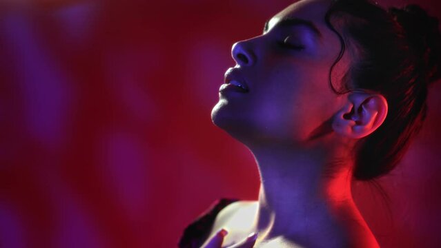 Fashion brunette woman seductive dancing movement touching lips neck dark futuristic gradient neon