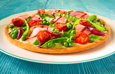 Pizza mit Tomaten und Erbsen mit roten Zweibeln auf türkisem Holzfond