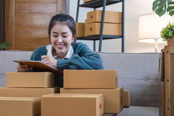 Portrait young attractive asian female owner startup business work happy with box at home prepare parcel delivery in sme supply chain, start up small business concept.