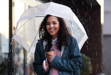 The rain makes way for new beginnings. a young woman holding an umbrella and coffee cup in the city.