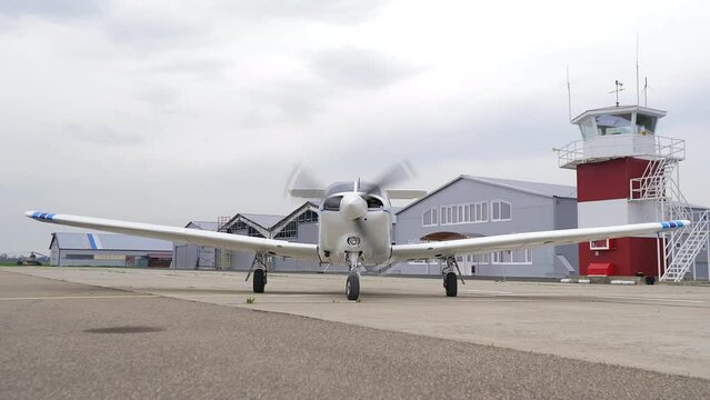 Single engine propeller airplane is standing in front of a closed aircraft hangar. Transportation for tourists and locals. Small white airplane existing hangar preparing for flight. 