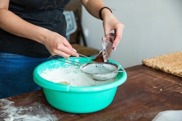 Housewife in process of baking delicious a cake in the kitchen - adding cacao to the cream