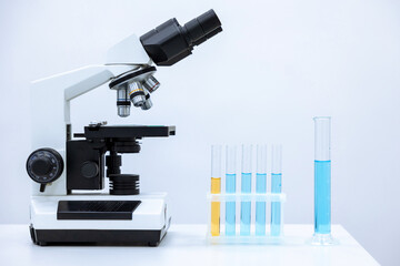 Laboratory glassware with color liquid and microscope, microbiologist or chemist place of work.