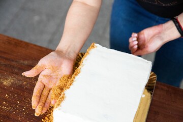 Housewife in the process of preparing delicious biscuit in the kitchen - adding the crumbs