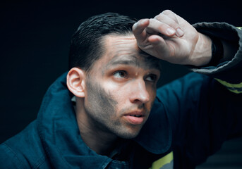 Its a risky business. Studio shot of a handsome young male firefighter looking thoughtful against a black background.