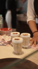 waitress serve a three glasses of iced white foamy latte coffee cappuccino in a coffee shop