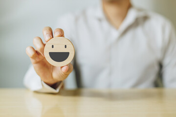 Customer show wood sphere smile face emoticon for rating. Service rating, feedback, satisfaction concept