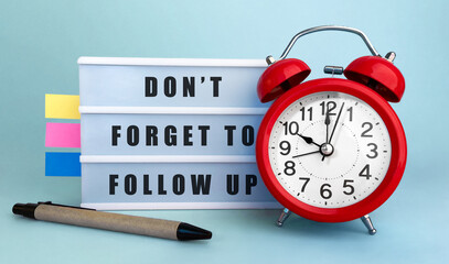 Text DONT FORGET TO FOLLOW UP written on the lightbox with alarm clock and colorfull stickers on...