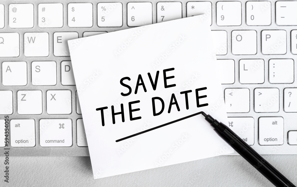 Poster white paper with text save the date? lying on the keyboard