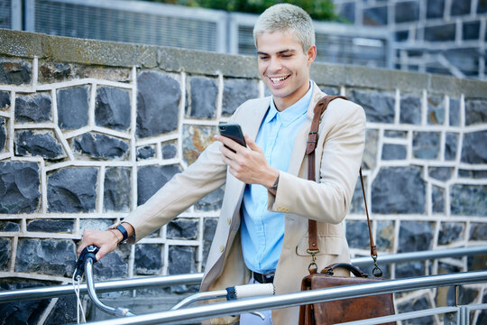 Squeezing in a quick social media browse before work. a handsome young businessman pushing his bicycle through the city while using his cellphone.