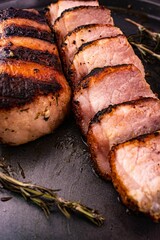 Close-up of a tray containing grilled meat, drizzled with a savory sauce