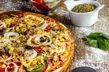Close-up shot of a freshly prepared pizza on a wooden platter surrounded by ingredients