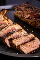 Close-up of a tray containing grilled meat, drizzled with a savory sauce