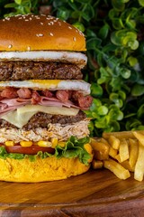 Delicious cheeseburger served with freshly-sliced tomatoes and corn on the cob, on a tabletop