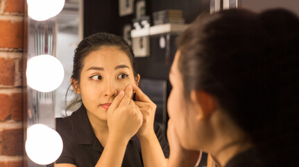 Asian woman Shocked woman squeezing pimple in make up mirror with fingers