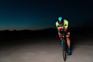 A triathlete rides his bike in the darkness of night, pushing himself to prepare for a marathon....