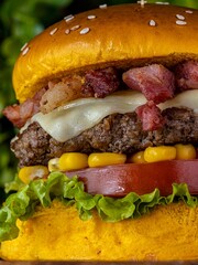 Delicious cheeseburger served with freshly-sliced tomatoes and corn on the cob, on a tabletop
