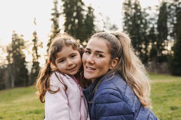 Fototapeta premium Happy mother and little daughter smiling on camera during trekking day at mountain forest - Family love - Mom day concept