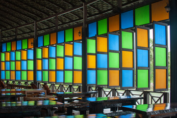 Colorful Window in the class room with many table and chair.