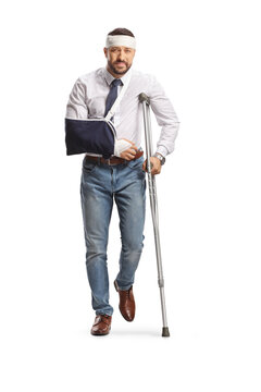 Young man with a broken arm and bandage on head leaning on a crutch